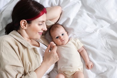Photo of Mother with her newborn baby on bed indoors, top view. Space for text