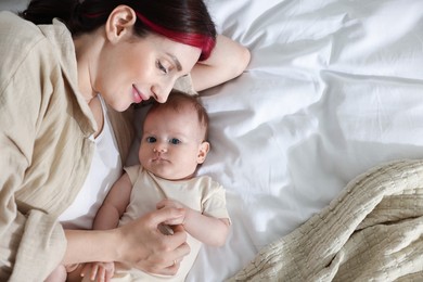 Photo of Mother with her newborn baby on bed indoors, top view. Space for text