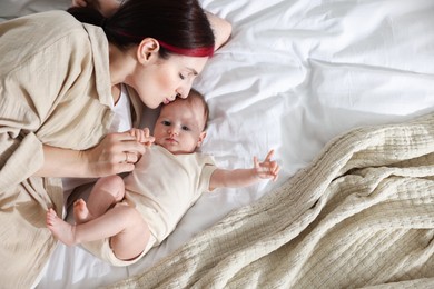 Photo of Mother with her newborn baby on bed indoors, top view. Space for text