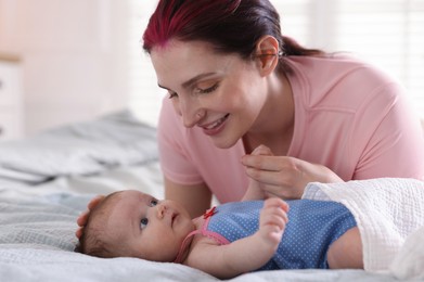 Photo of Mother putting her cute newborn baby to sleep on bed at home