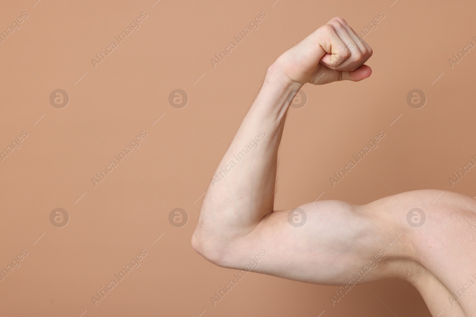 Man showing his bicep on beige background, closeup. Space for text Photo of Man showing his bicep on beige background, closeup. Space for text