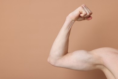 Photo of Man showing his bicep on beige background, closeup. Space for text
