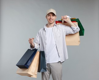 Photo of Cheerful man with shopping bags on light grey background
