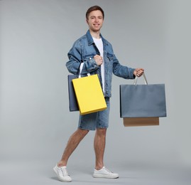 Photo of Cheerful man with shopping bags on light grey background