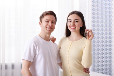 Photo of Happy couple with key of their new house indoors