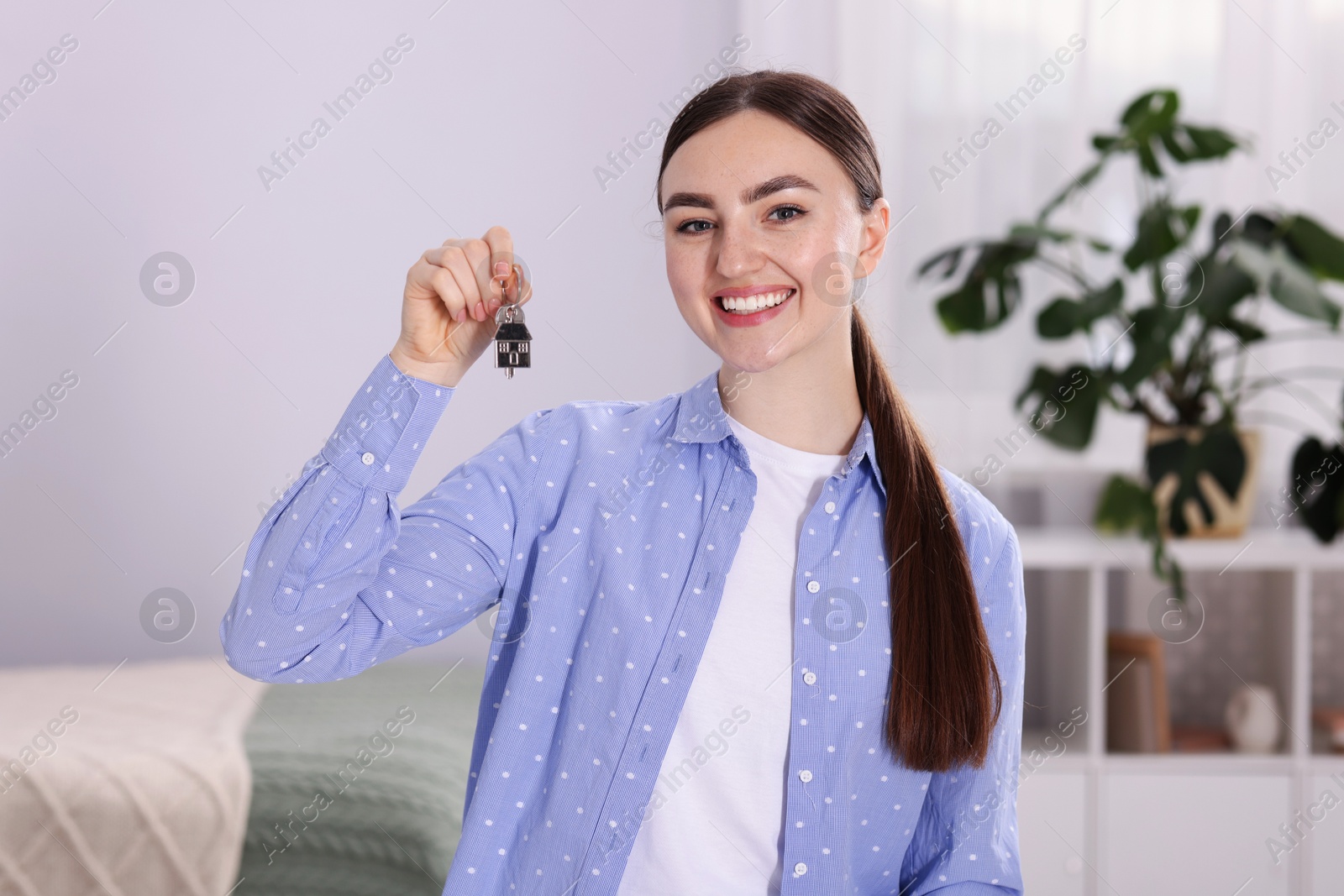 Happy woman with key of her new apartment indoors Photo of Happy woman with key of her new apartment indoors