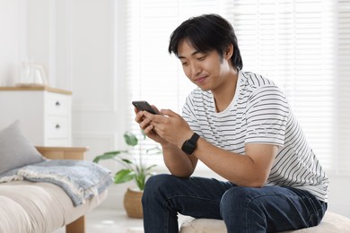 Photo of Handsome Asian man with smartphone at home