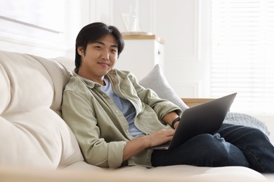 Photo of Handsome Asian man with laptop on sofa at home