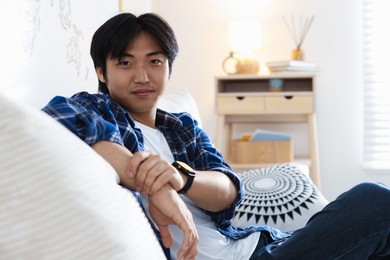 Photo of Handsome Asian man sitting on sofa at home