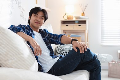Photo of Handsome Asian man sitting on sofa at home