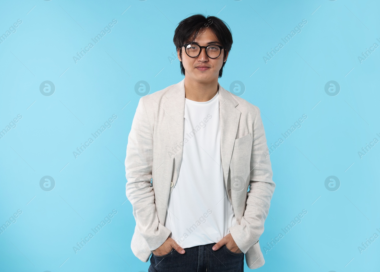 Handsome Asian businessman in glasses on light blue background Photo of Handsome Asian businessman in glasses on light blue background
