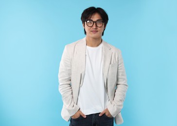 Photo of Handsome Asian businessman in glasses on light blue background