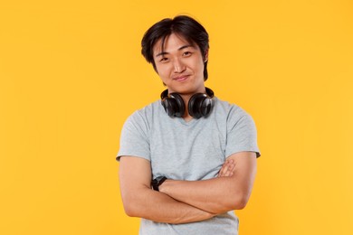 Photo of Portrait of handsome Asian man with headphones on yellow background