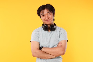 Photo of Portrait of handsome Asian man with headphones on yellow background