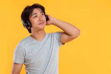 Photo of Handsome Asian man in headphones on yellow background