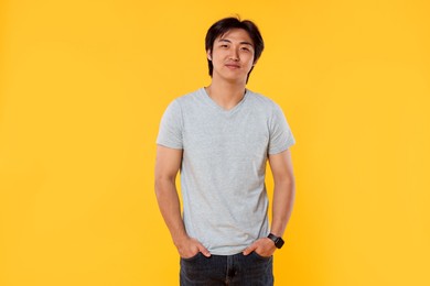 Photo of Portrait of handsome Asian man on yellow background