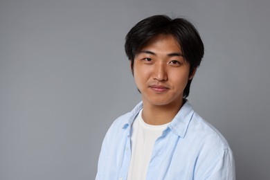Photo of Portrait of handsome Asian man on grey background. Space for text