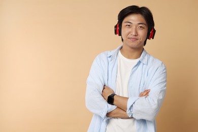 Photo of Handsome Asian man in headphones on beige background. Space for text