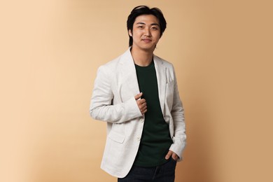 Photo of Portrait of handsome Asian businessman in suit on beige background