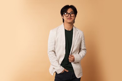 Photo of Portrait of handsome Asian businessman in glasses on beige background. Space for text