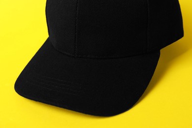 Photo of Black baseball hat on yellow background, closeup