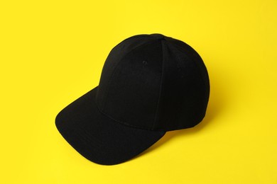 Photo of One black baseball hat on yellow background