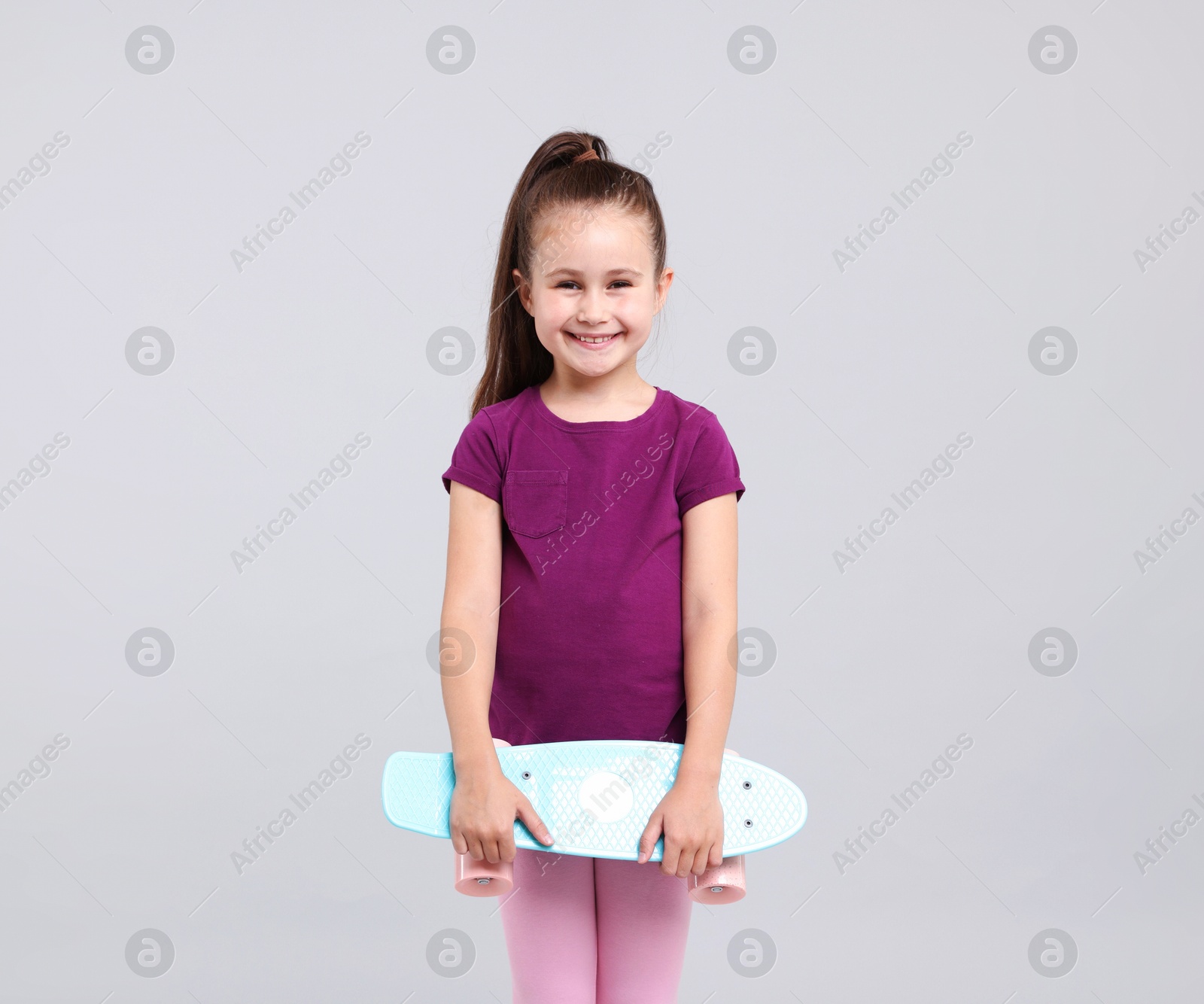 Little girl with penny board on light grey background Photo of Little girl with penny board on light grey background