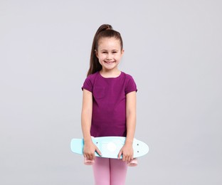 Photo of Little girl with penny board on light grey background