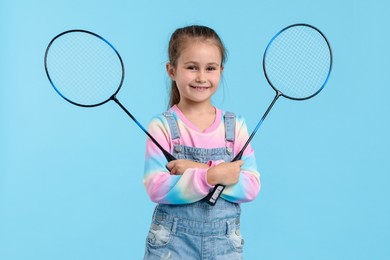 Photo of Little girl with tennis rackets on light blue background