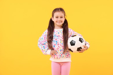 Photo of Little girl with soccer ball on yellow background