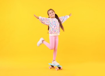 Photo of Little girl with penny board on yellow background