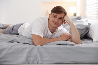 Photo of Young man lying on bed with soft mattress at home
