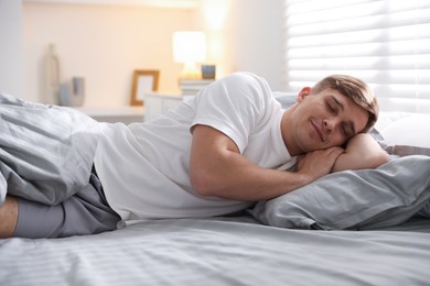 Photo of Young man sleeping on bed with soft mattress at home