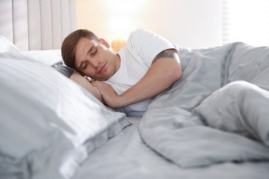 Photo of Young man sleeping on bed with soft mattress at home