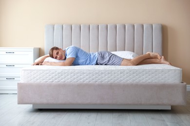 Photo of Young man lying on bed with soft mattress at home