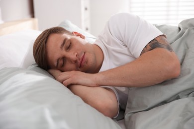 Photo of Young man sleeping on bed with soft mattress at home