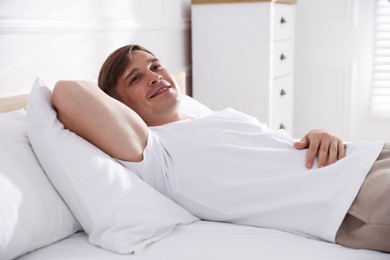 Photo of Young man lying on bed with soft mattress at home