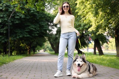 Photo of Happy woman with her cute Alaskan malamute dog in park. Space for text