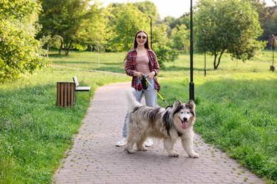 Photo of Happy woman walking with her cute Alaskan malamute dog in park