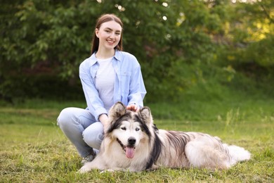Photo of Happy woman with her cute Alaskan malamute dog on green grass outdoors