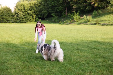 Photo of Smiling woman with her cute Alaskan malamute dog on green grass outdoors