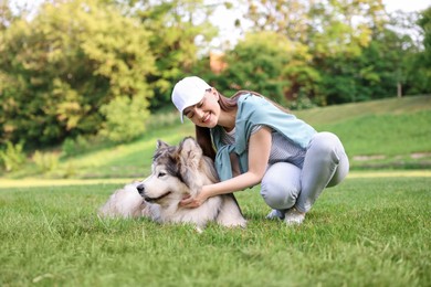 Photo of Smiling woman with her cute Alaskan malamute dog on green grass outdoors
