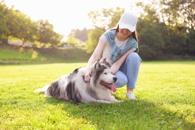 Photo of Smiling woman with her cute Alaskan malamute dog on green grass outdoors in morning