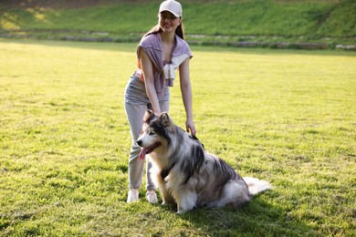 Photo of Smiling woman with her cute Alaskan malamute dog on green grass outdoors in morning