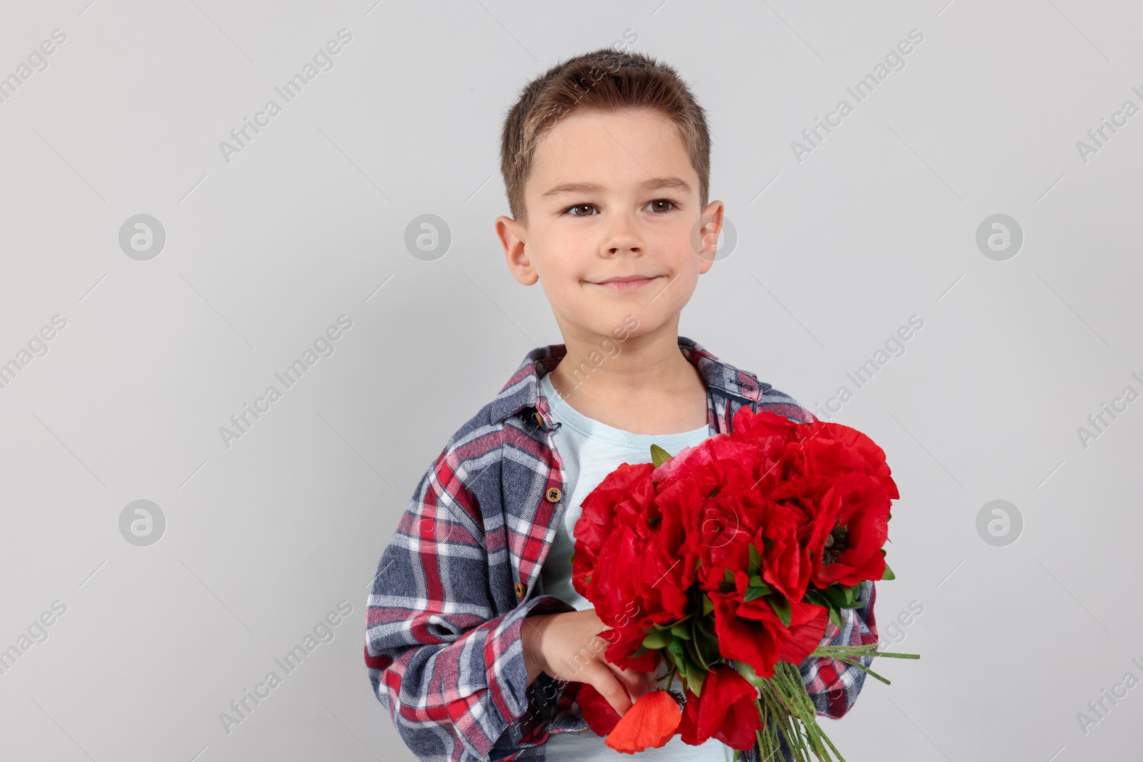 Portrait of cute little boy with bouquet of beautiful flowers on light grey background Photo of Portrait of cute little boy with bouquet of beautiful flowers on light grey background