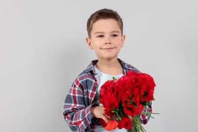 Photo of Portrait of cute little boy with bouquet of beautiful flowers on light grey background