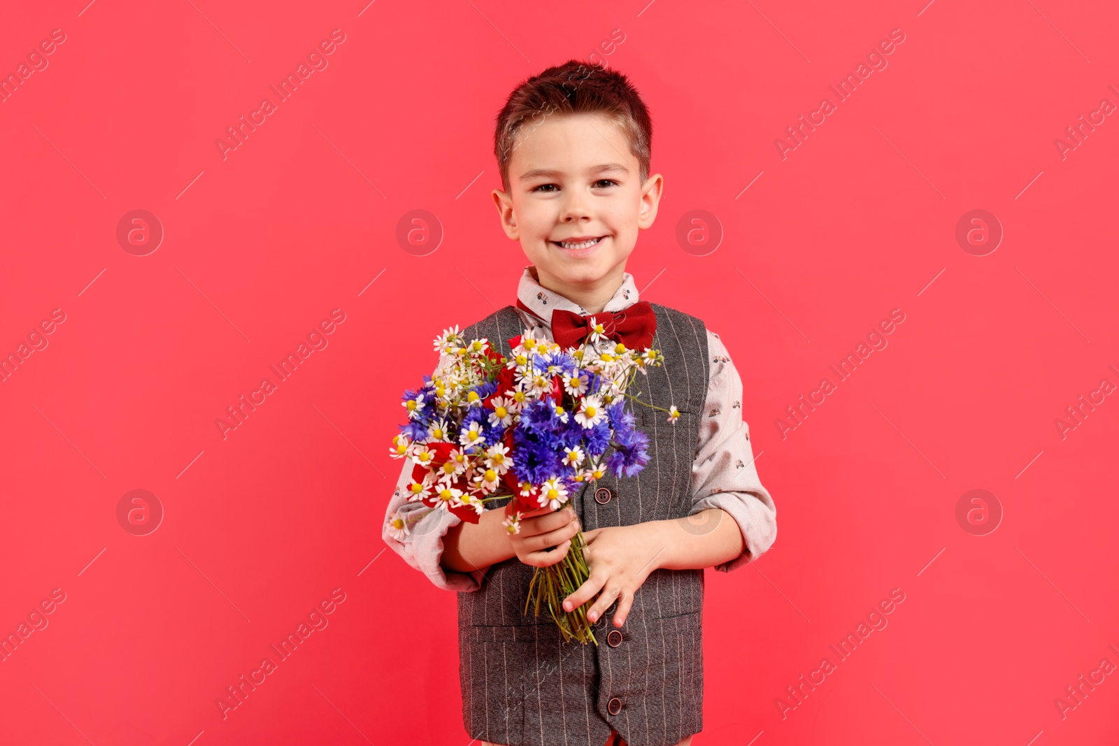 Portrait of smiling little boy with bouquet of beautiful flowers on red background Photo of Portrait of smiling little boy with bouquet of beautiful flowers on red background