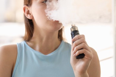 Photo of Young woman using electronic smoking device outdoors, closeup