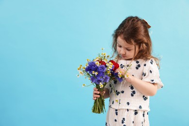 Photo of Cute little girl with bouquet of beautiful flowers on light blue background, space for text