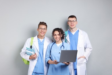 Photo of Group of medical students with laptop and books on light grey background